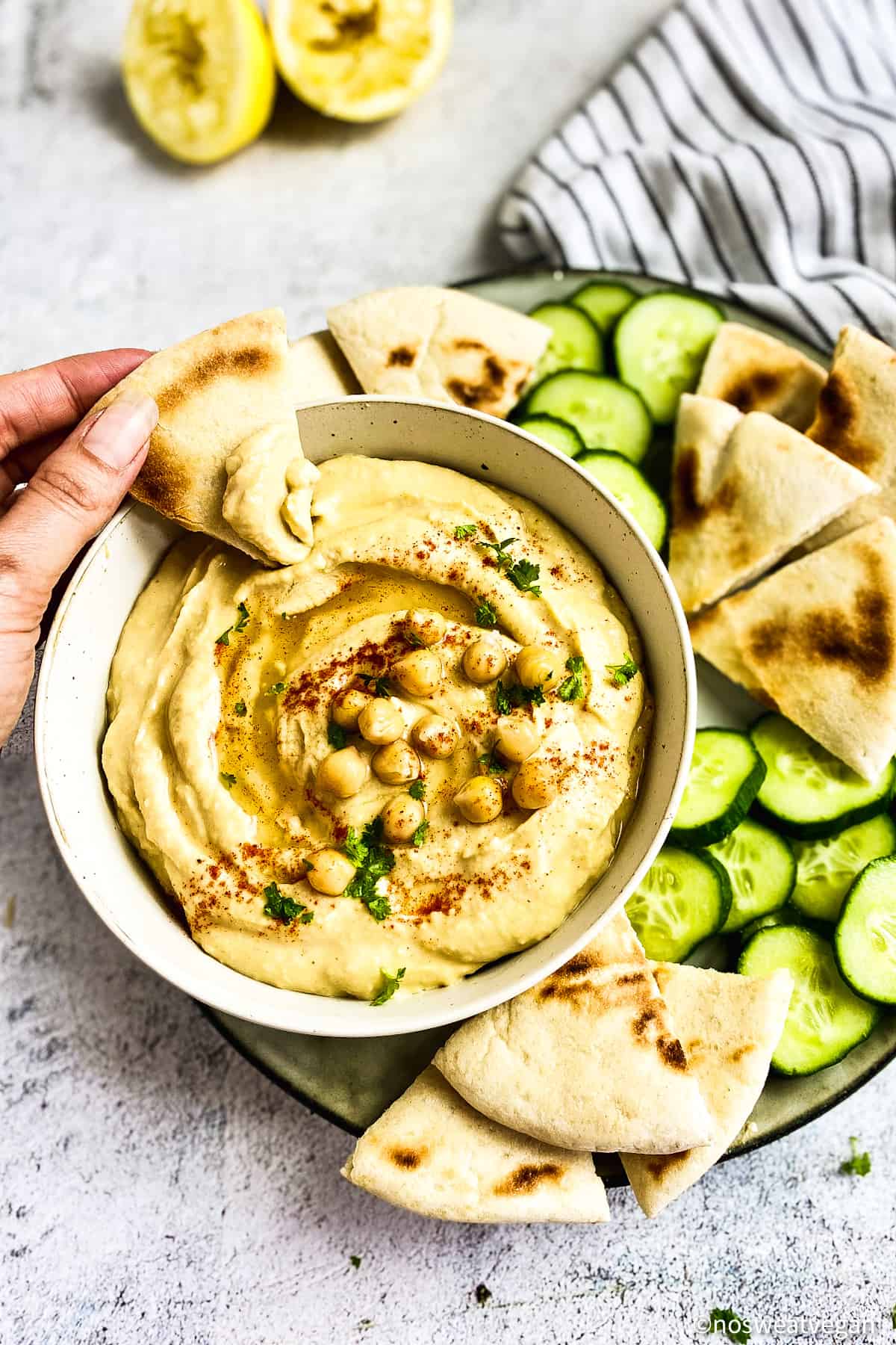 Hand dipping pit into oil-free hummus.