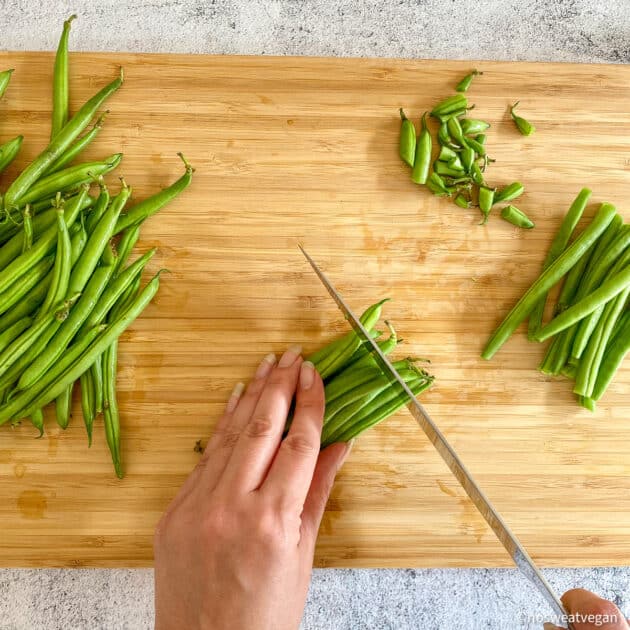 Hands trimming fresh green beans.