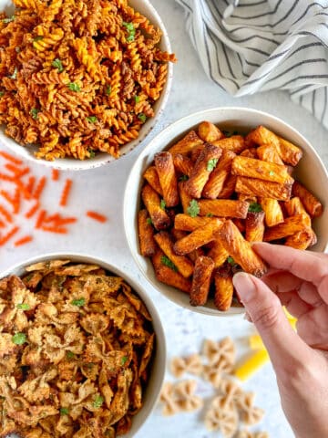 Three bowls with pasta chips and a hand holding one of the chips.