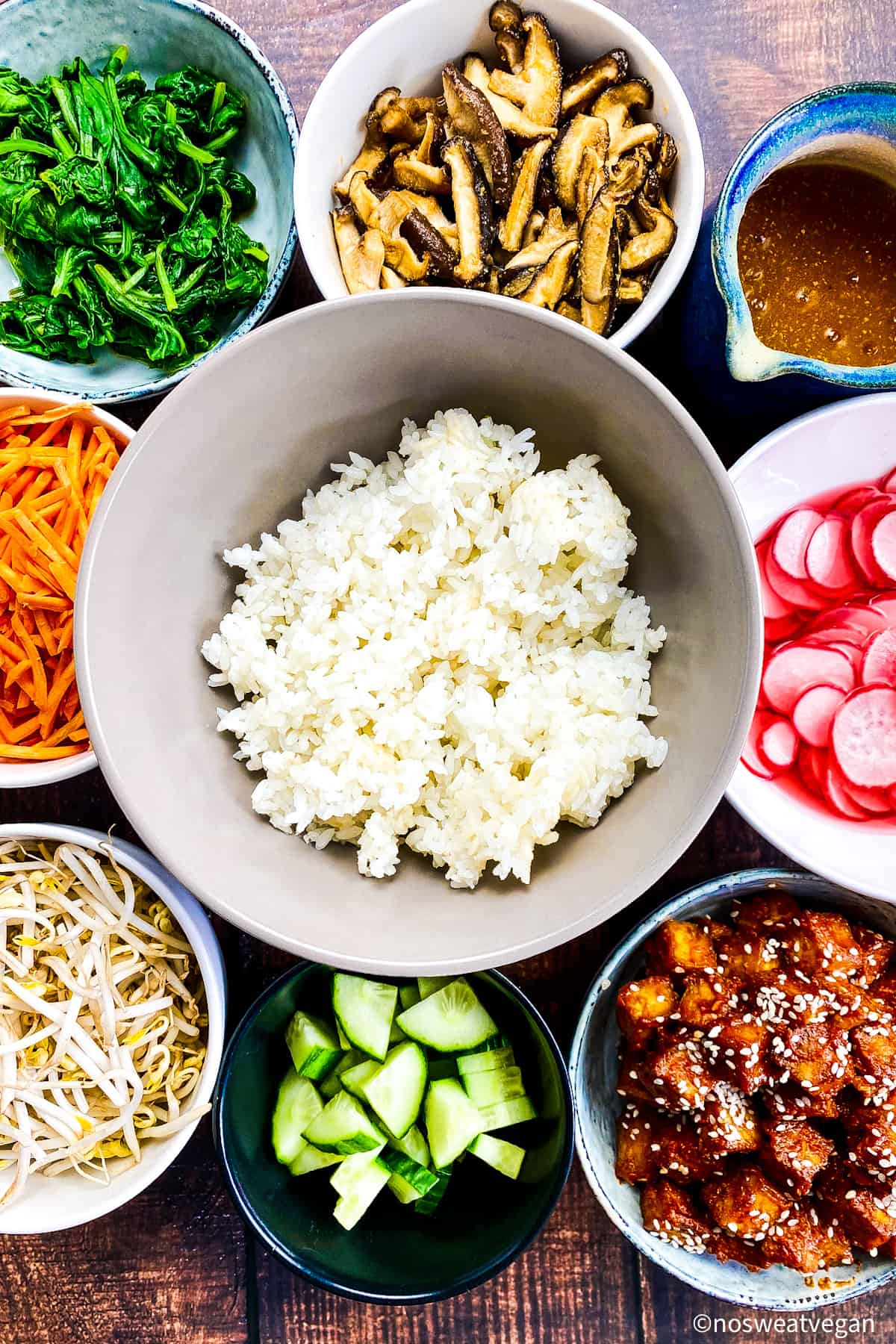 Bowl of rice surrounded by small bowls with the other bibimbap ingredients.