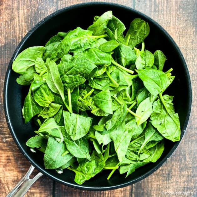 Uncooked spinach in skillet.