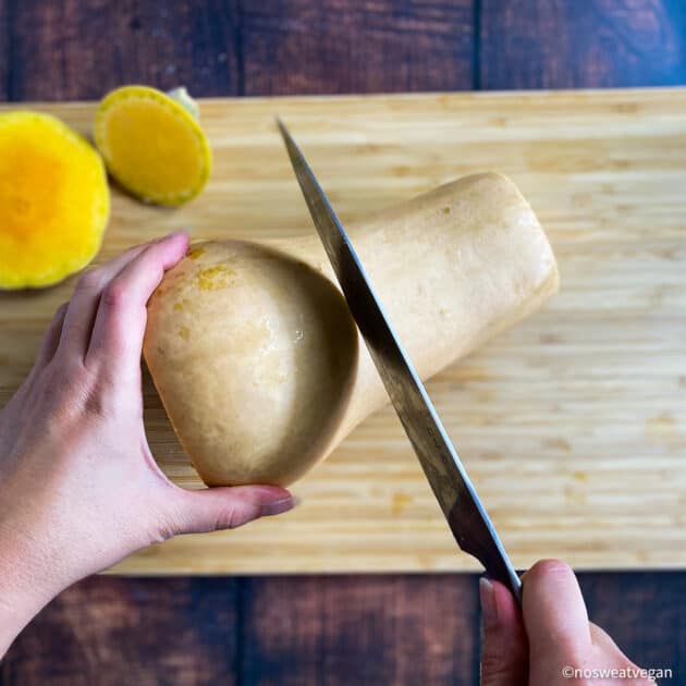Hand cutting butternut squash in half.