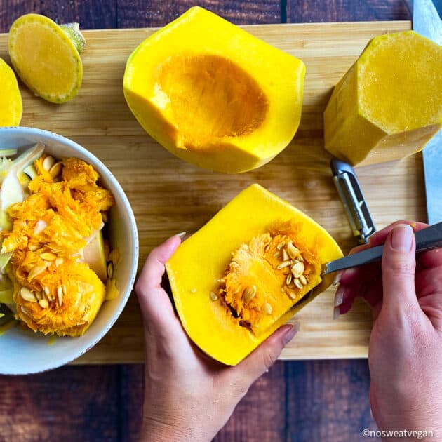 Hand removing butternut squash seeds.