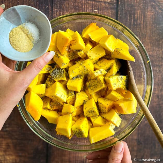 Butternut squash in mixing bowl with seasonings.
