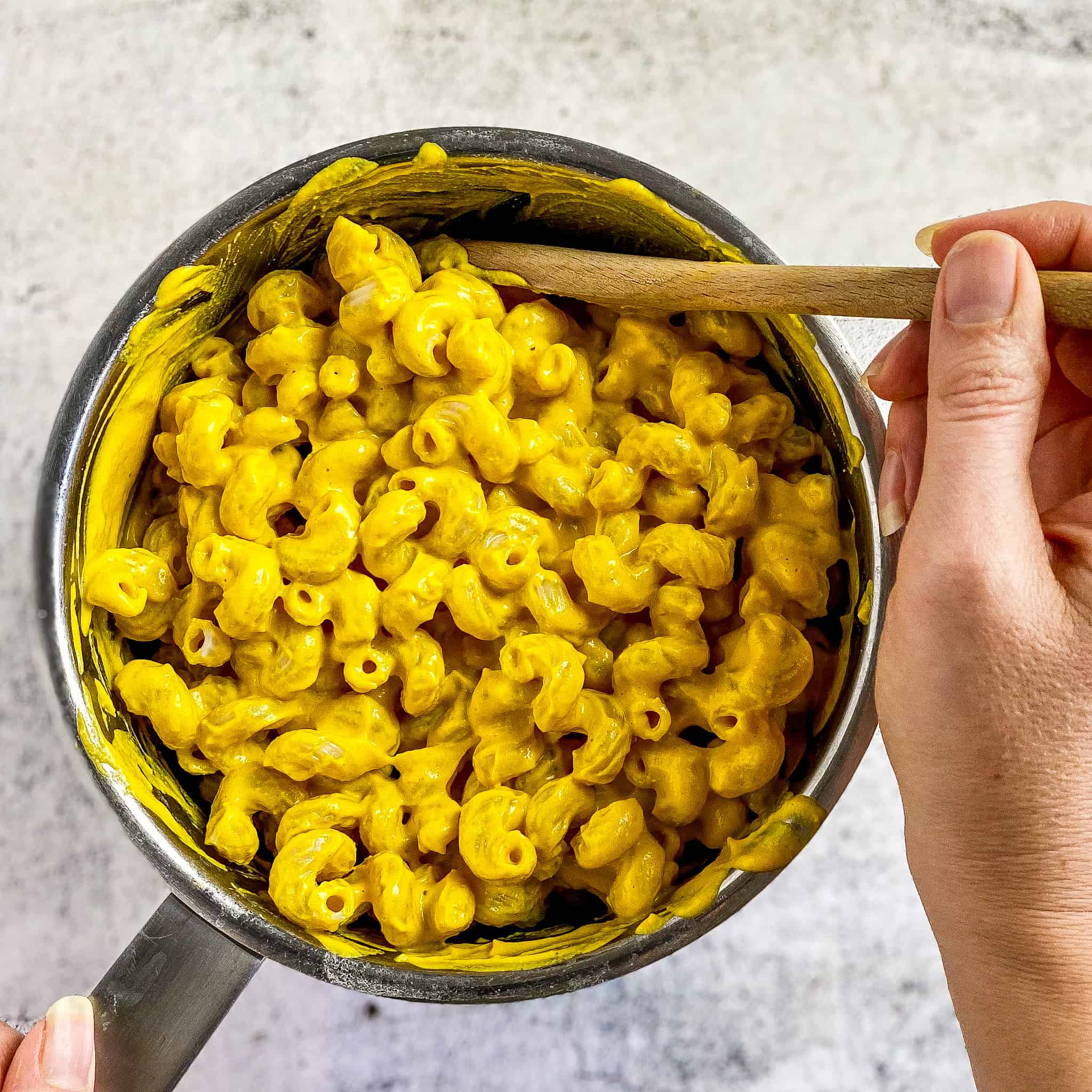 Macaroni mixed with vegan pumpkin cheese sauce.
