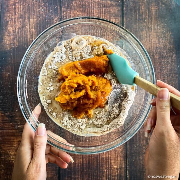 Hand mixing wet ingredients for vegan pumpkin muffins.