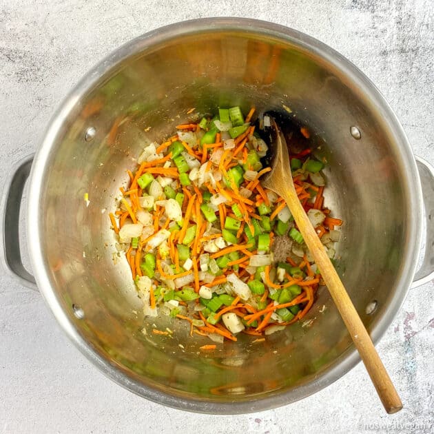 Carrots, onions, and celery cooking in a soup pot.