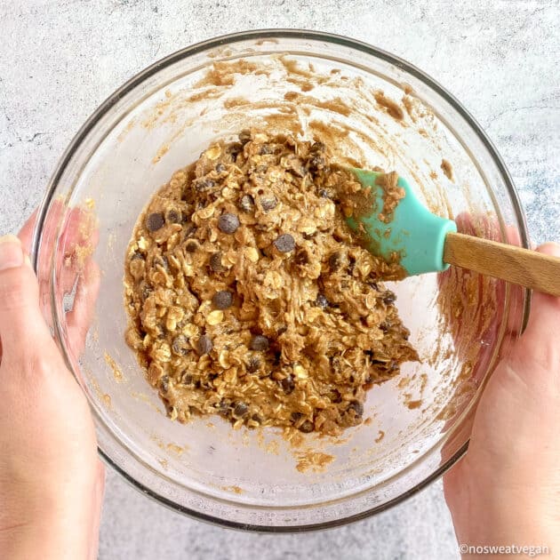Vegan oatmeal cookie batter in bowl with chocolate chips.