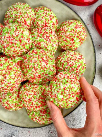 Best vegan Christmas cookies on a plate with a hand picking one up.