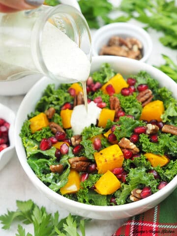 Holiday kale salad with dressing pouring over it.