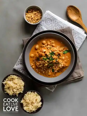 Vegetarian massaman curry in a bowl with two small bowls of rice.