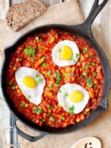Vegan chickpea shakshuka in skillet with vegan fried eggs.