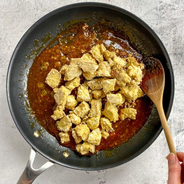 Tofu added to General Tso's sauce in skillet.