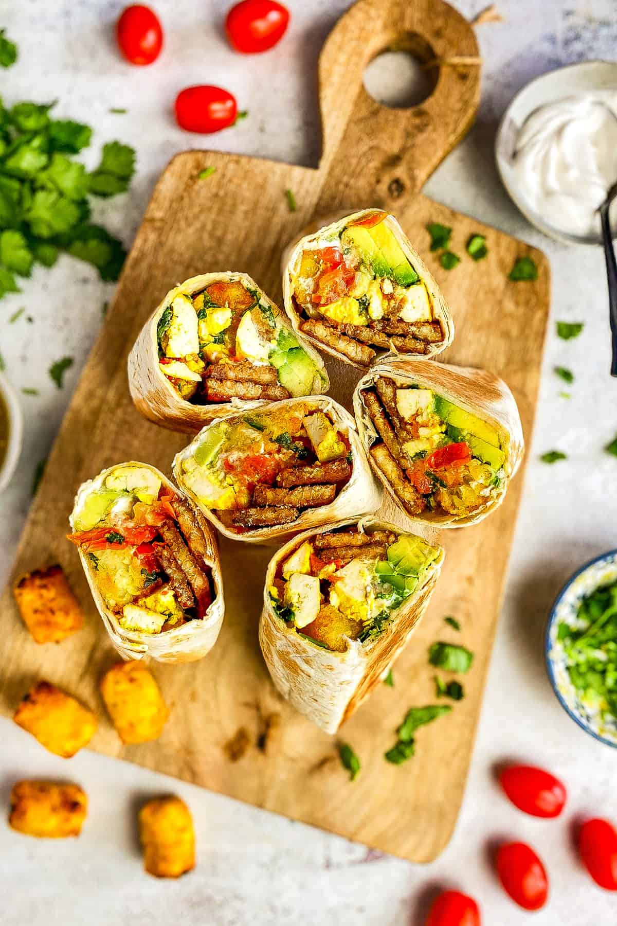 Vegan breakfast burritos cut in half and face up on a cutting board.