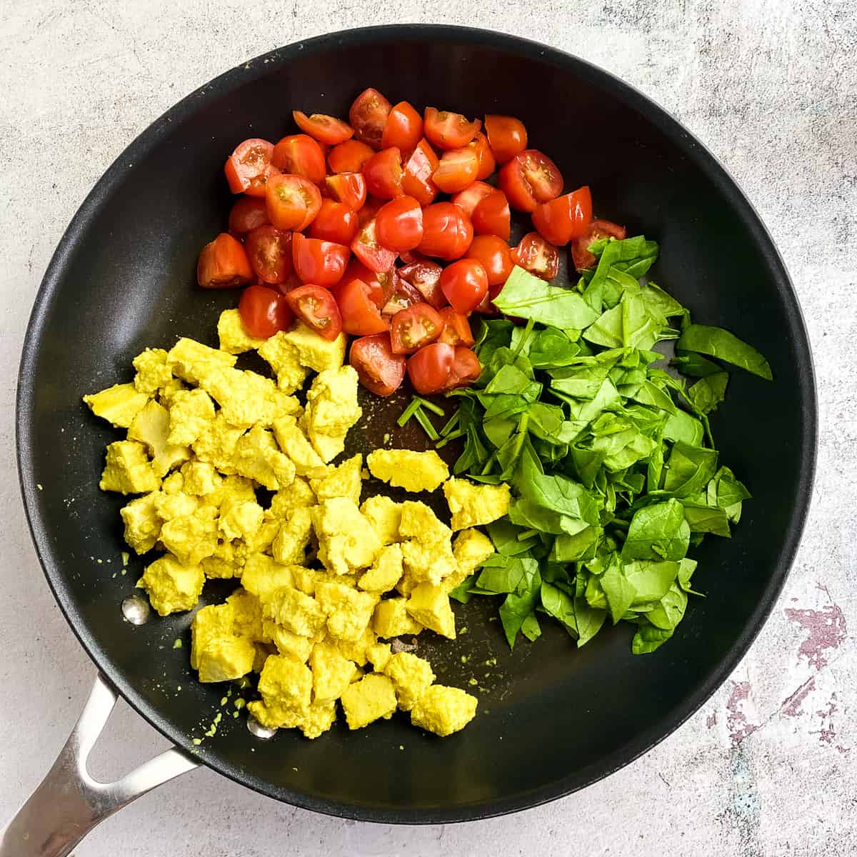 Tofu scramble with tomatoes and spinach for breakfast burrito.