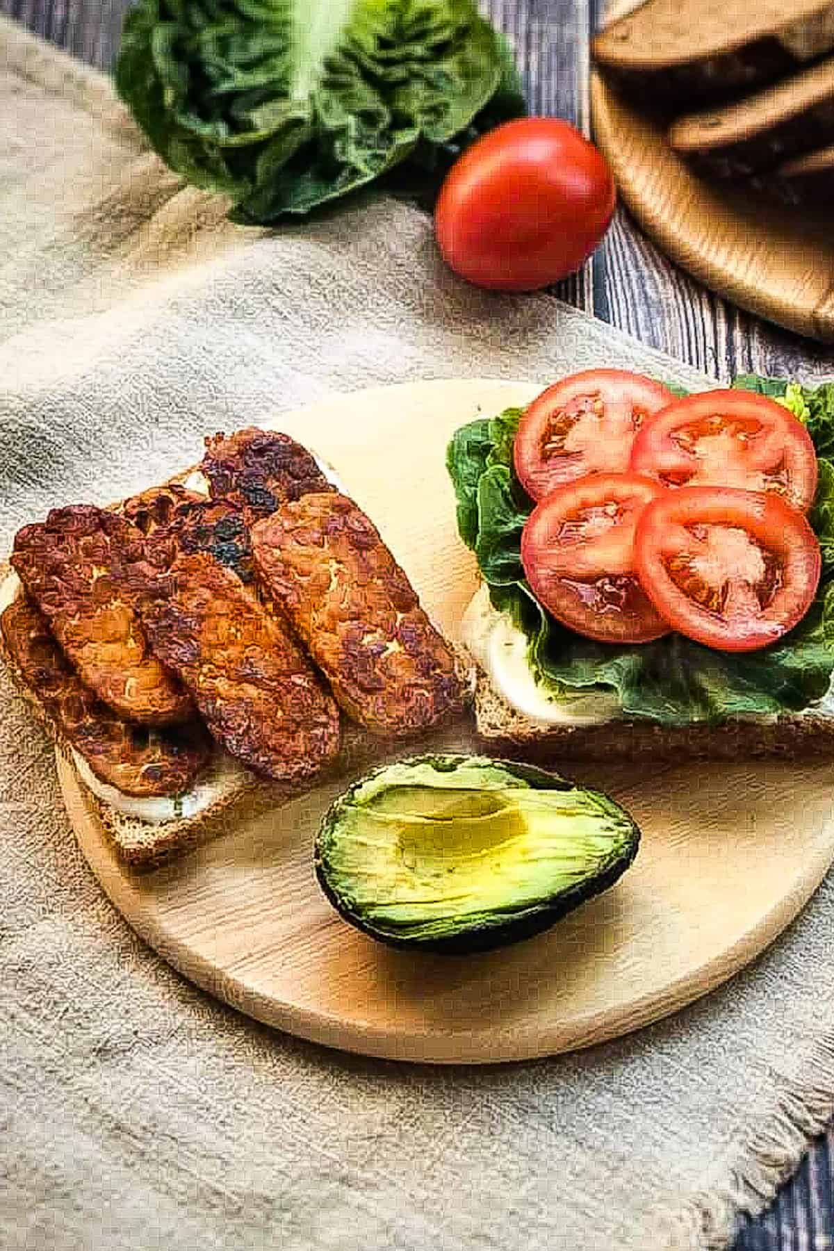 Vegan BLT open on cutting board with avocado.