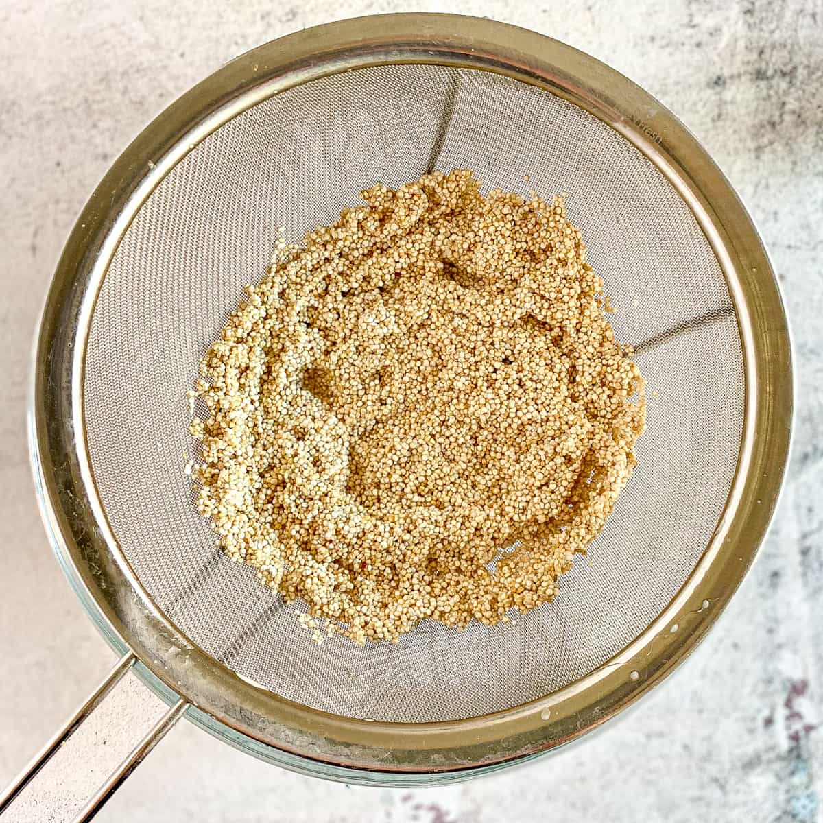 Quinoa rinsed in a mesh strainer.