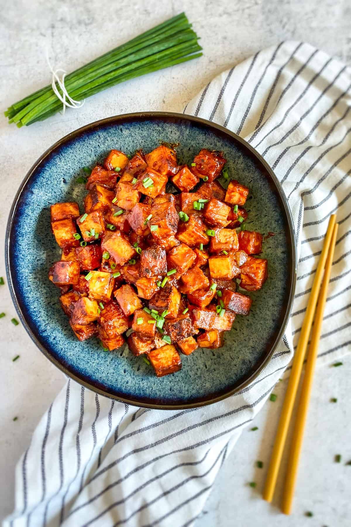 Marinated tofu in a bowl next to chopsticks.