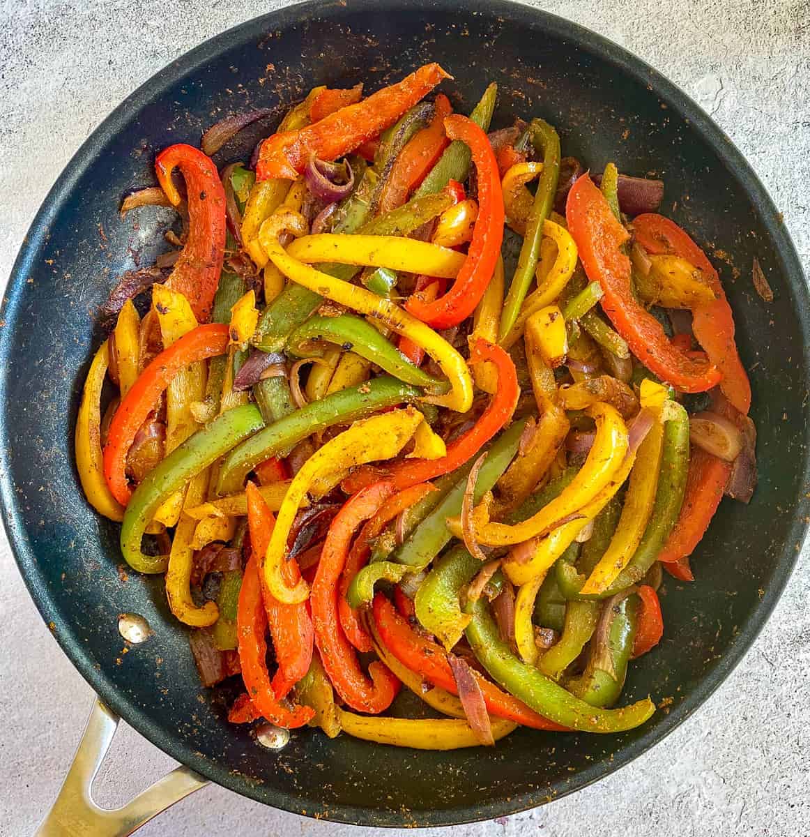 Cooked fajita veggies in a skillet.