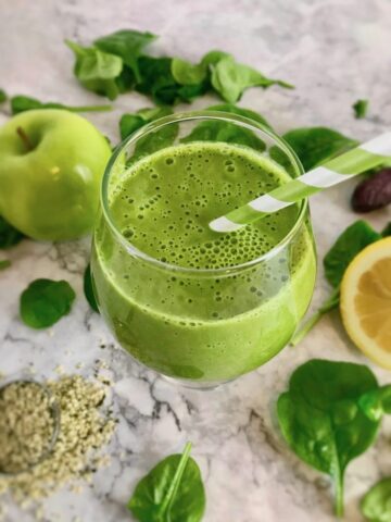 Spinach apple smoothie with straw.