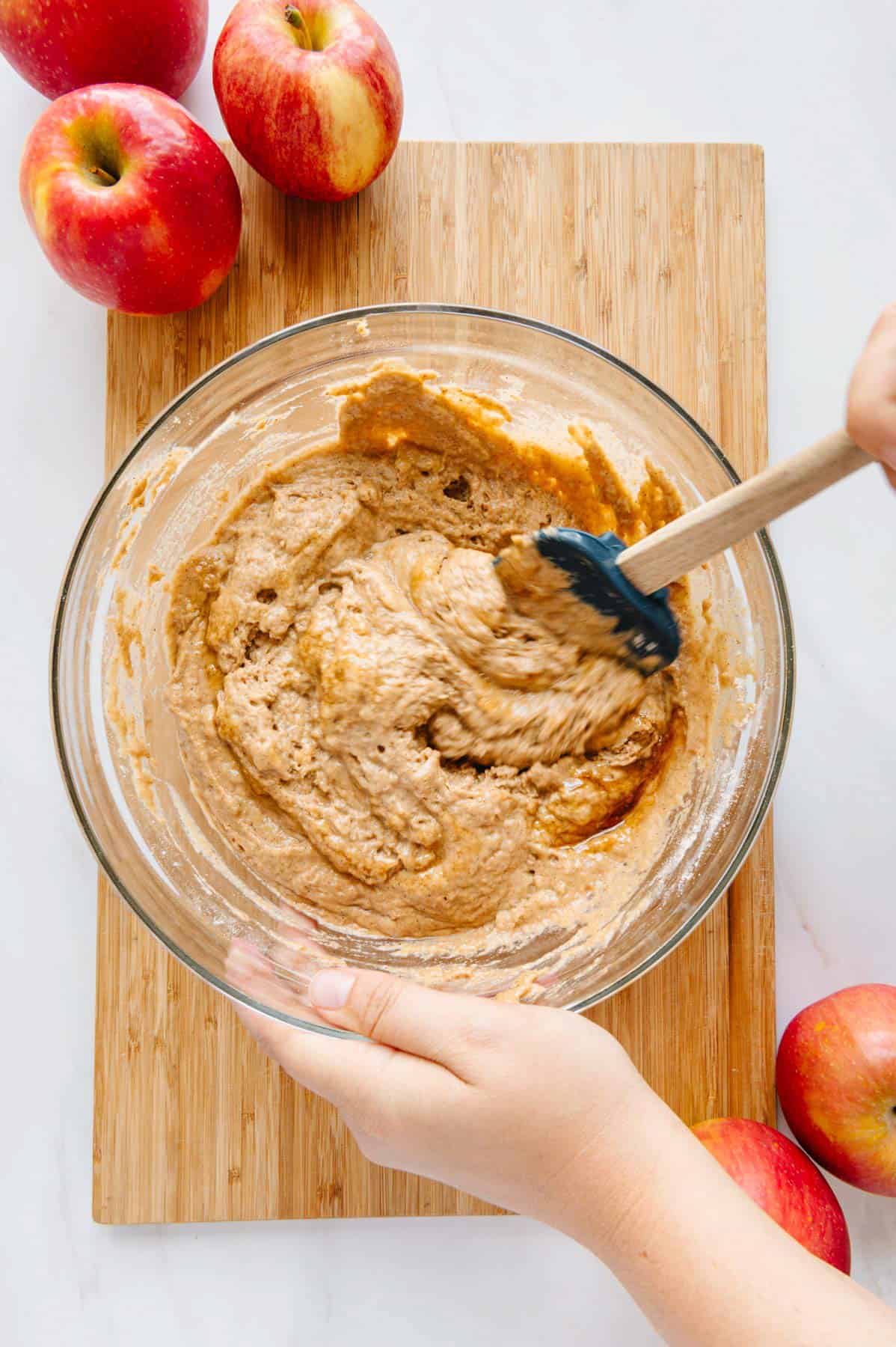 Muffin batter in bowl with two hands mixing it.