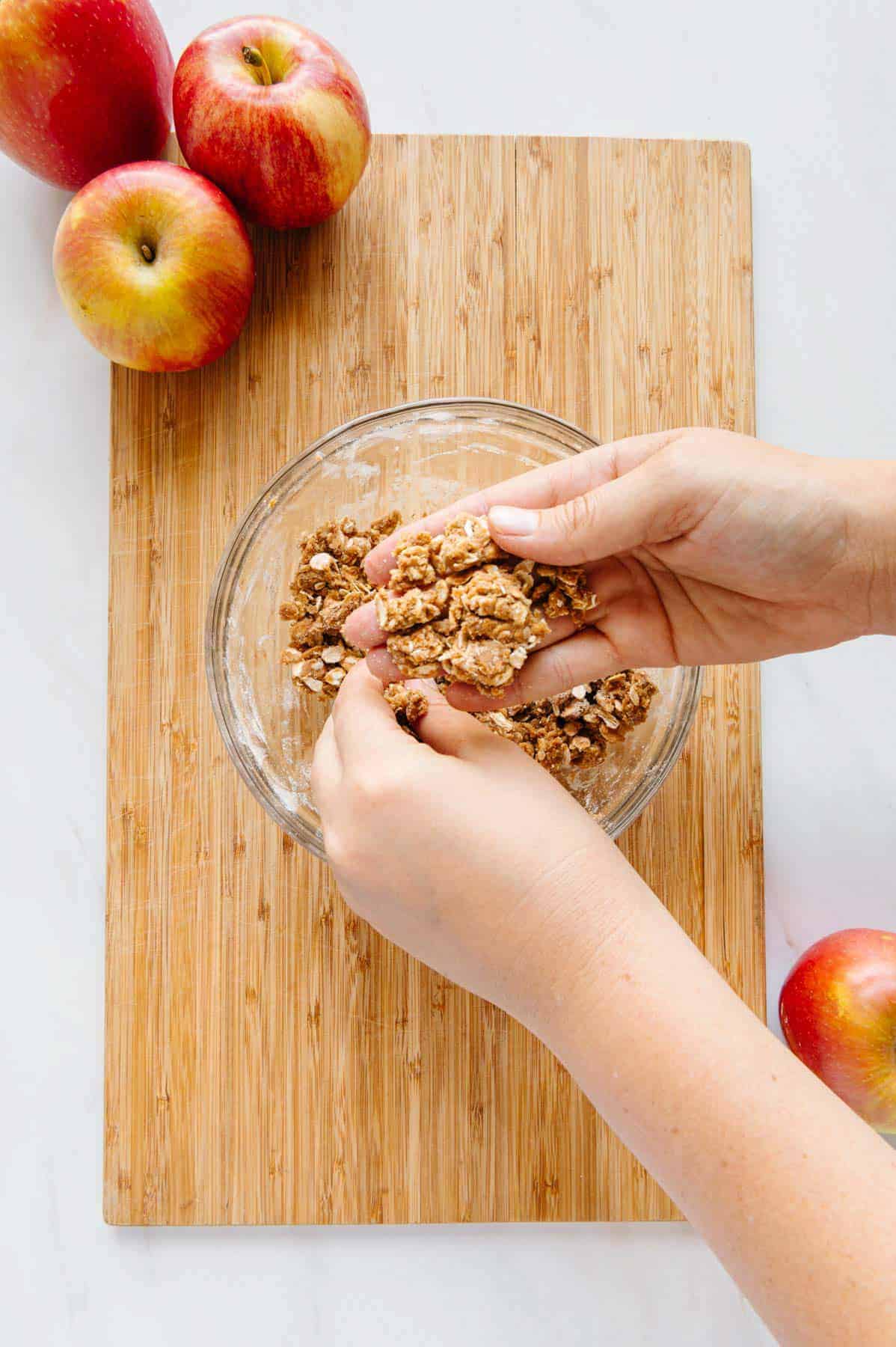 Hands breaking up streusel topping.