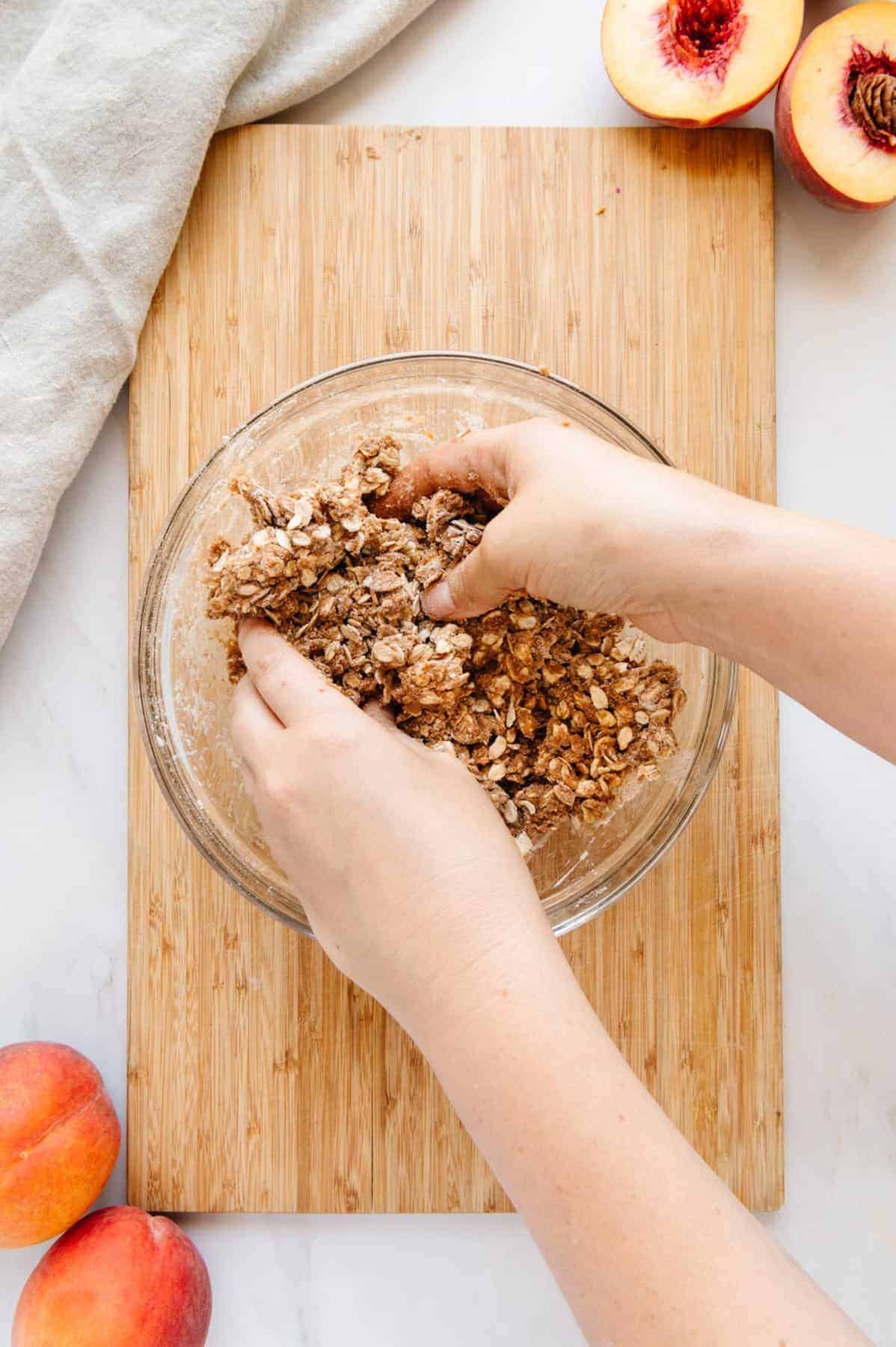 Hands mixing crumble topping.
