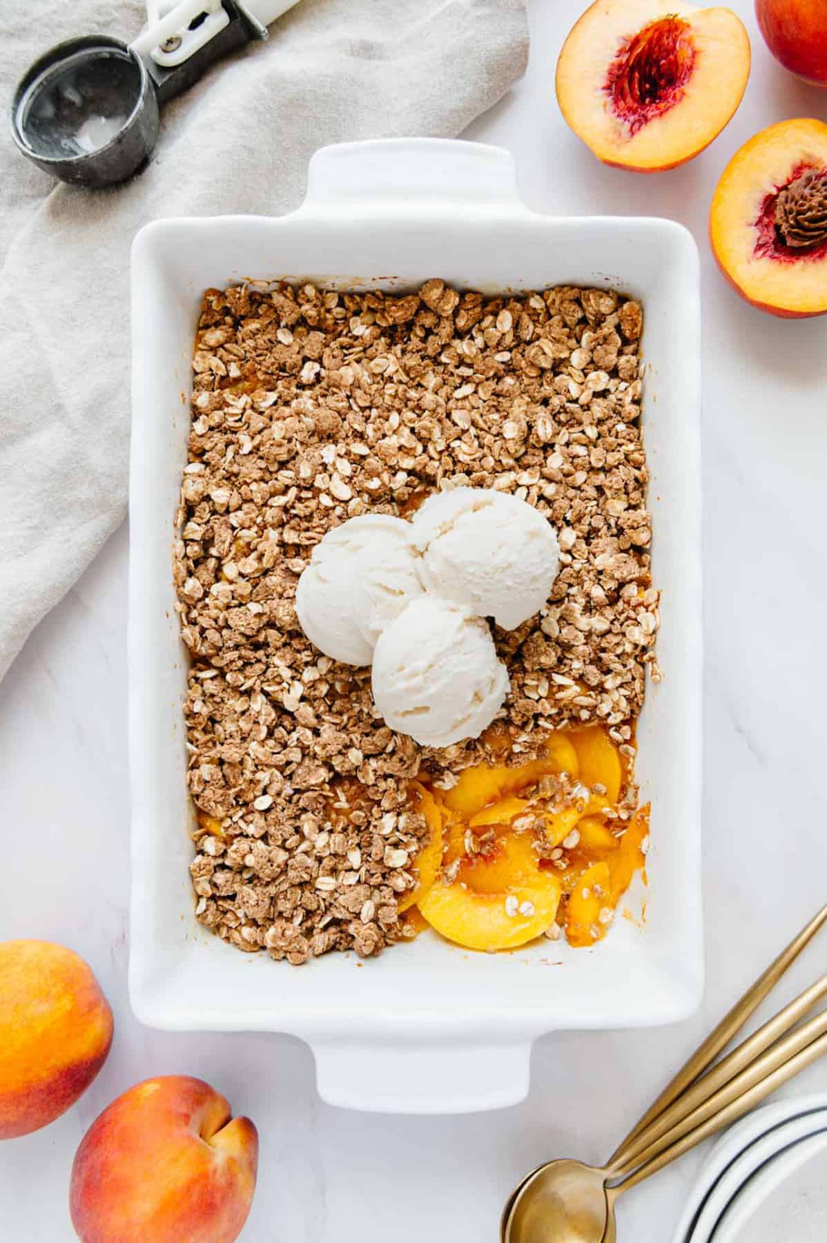 Vegan peach crisp topped with three scoops of ice cream.