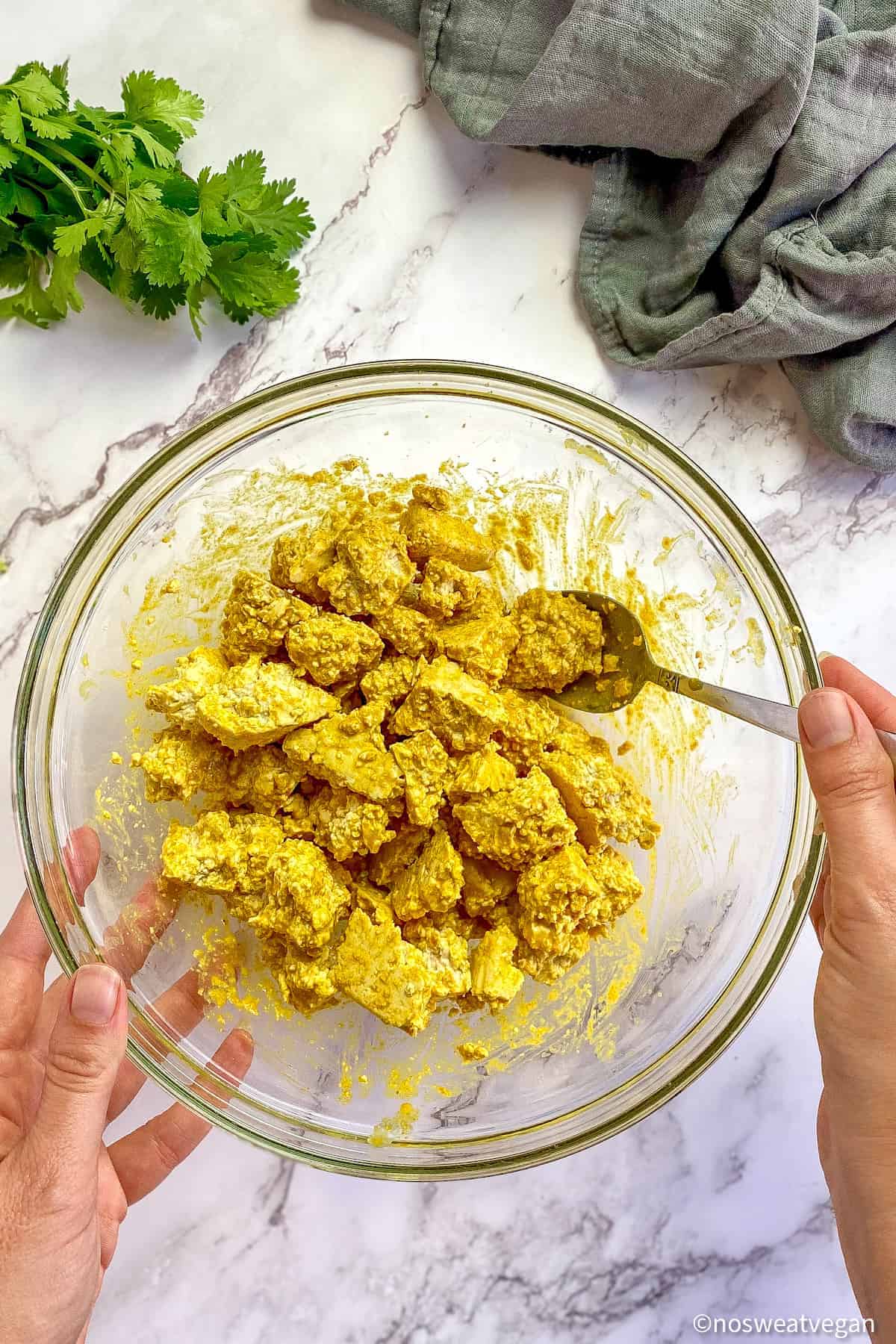 Tofu chunks mixed with curry paste in a bowl.
