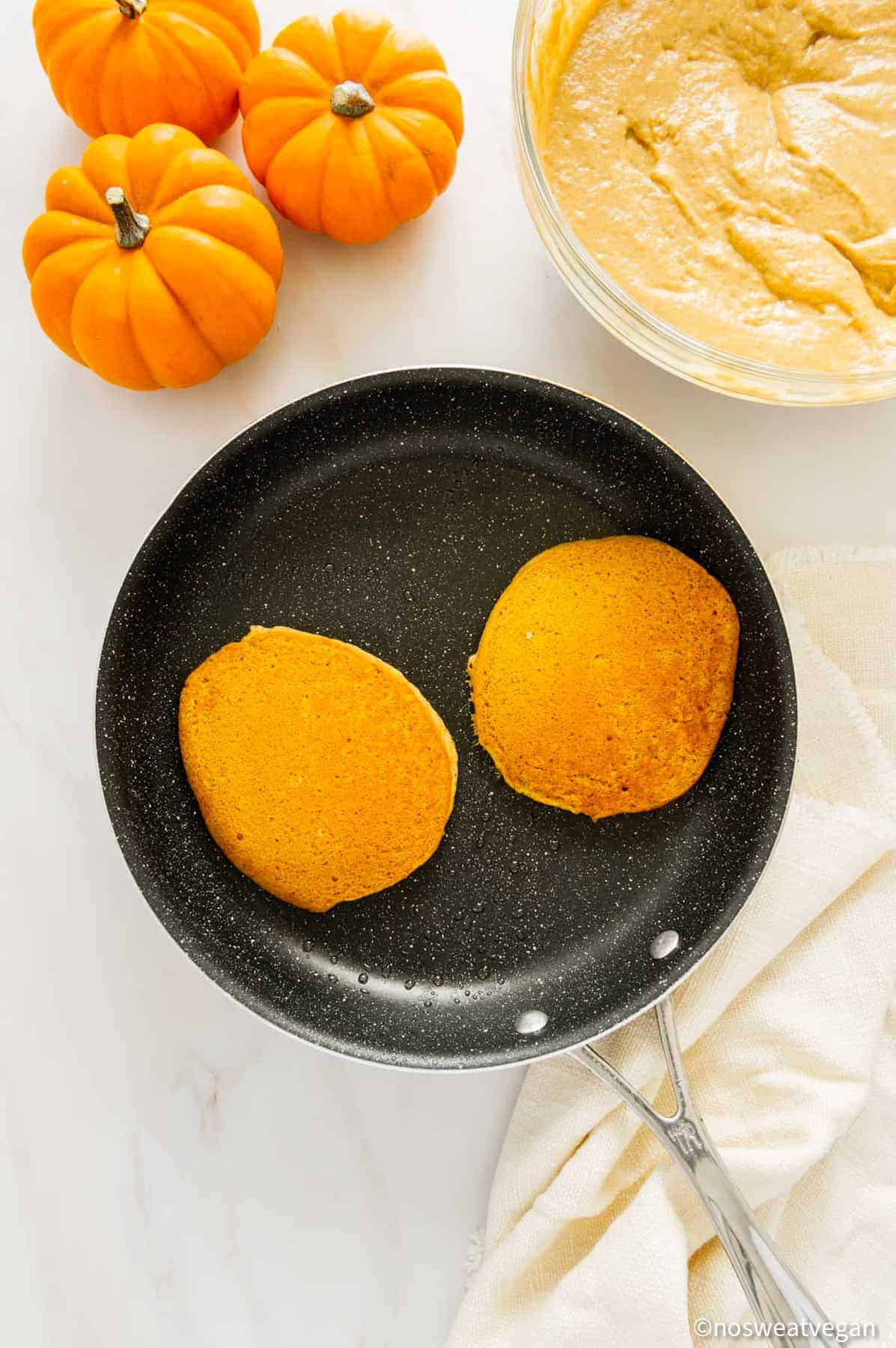 Oil-free pumpkin pancakes cooked in a skillet.
