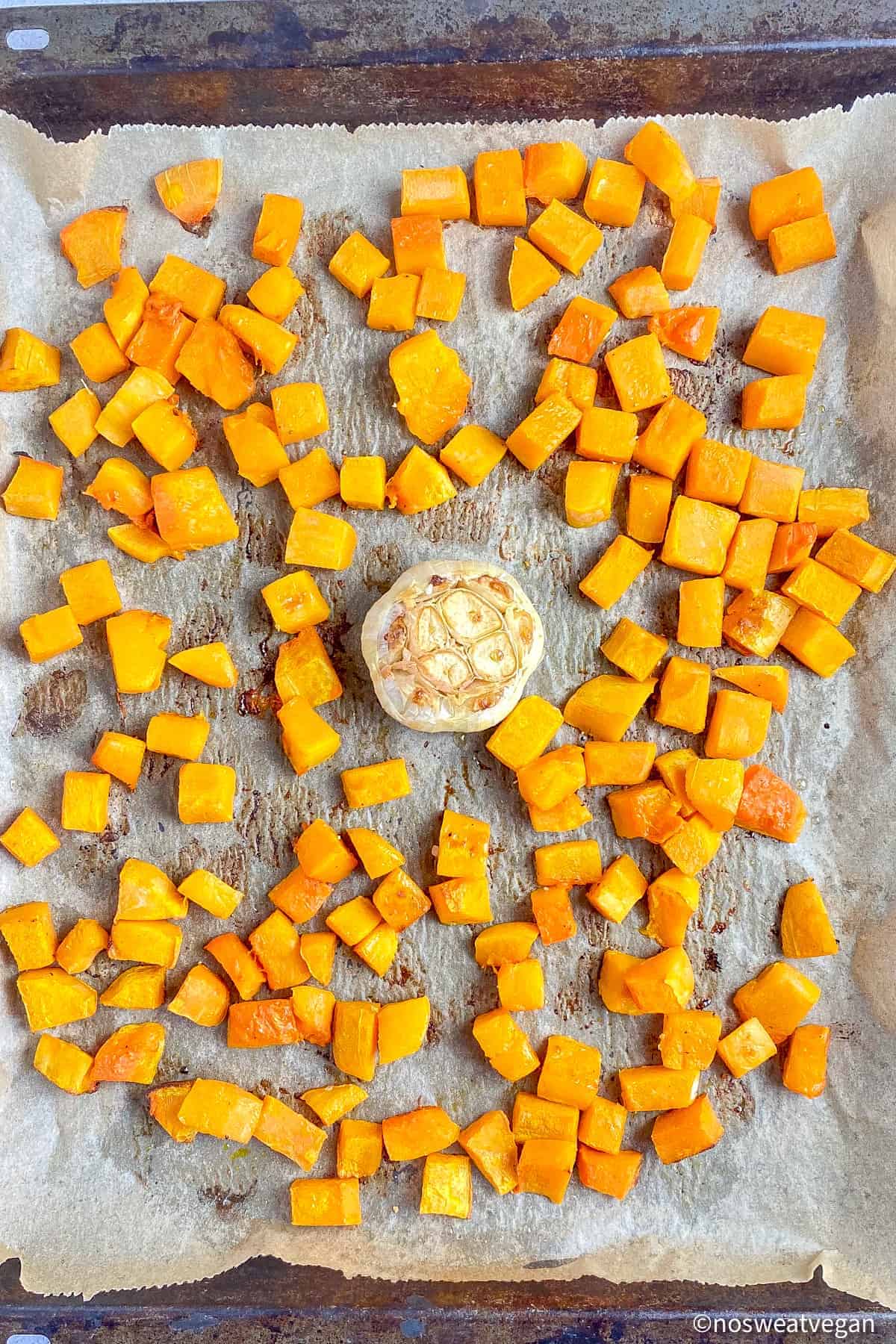 Roasted butternut squash and garlic on sheet pan.