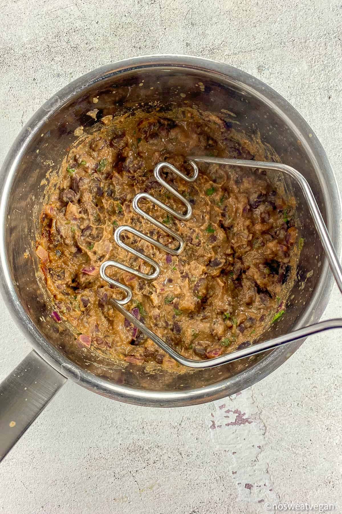 Smashed black beans in a pot.
