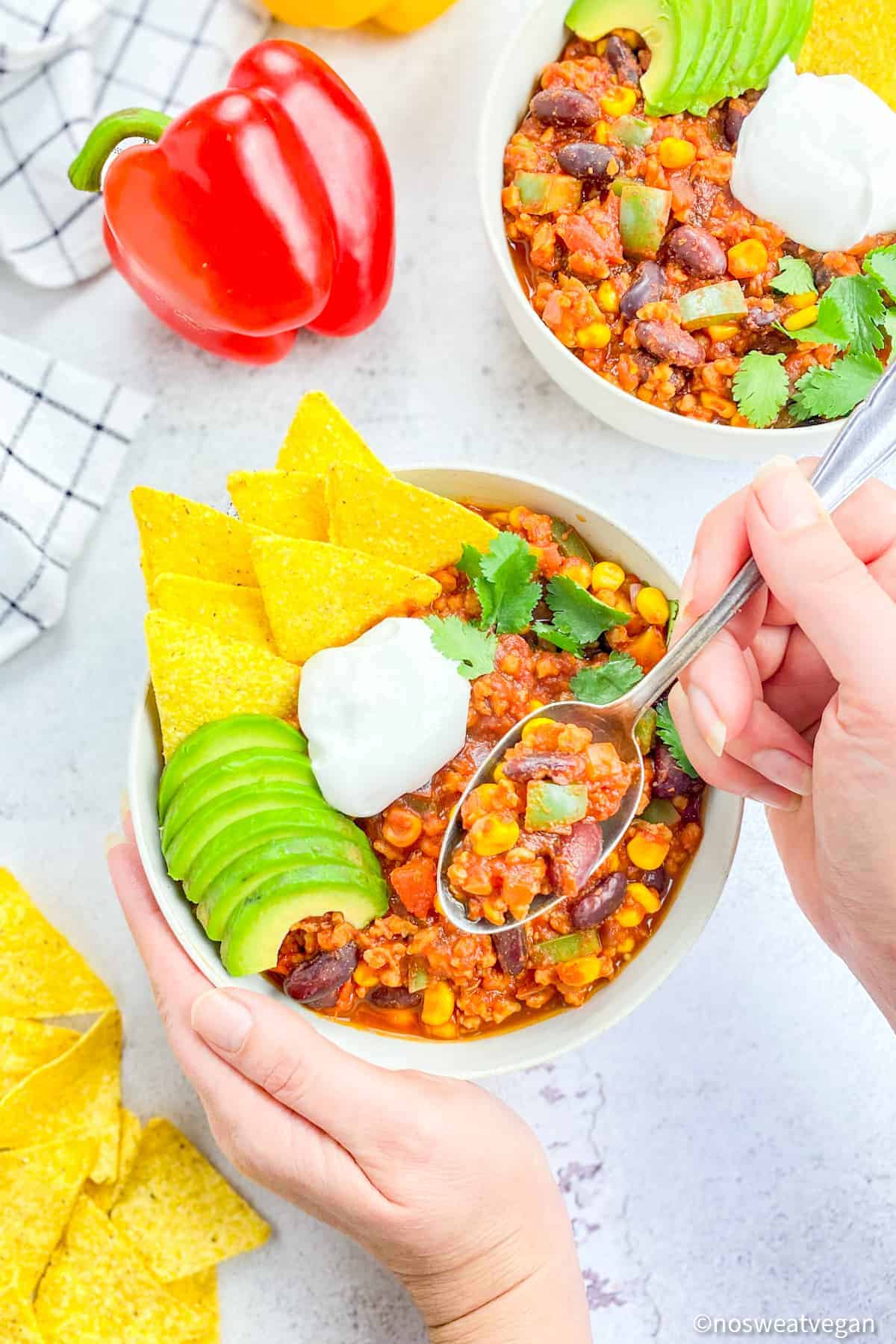 Bowl with hand lifting a spoonful of chili sin carne.