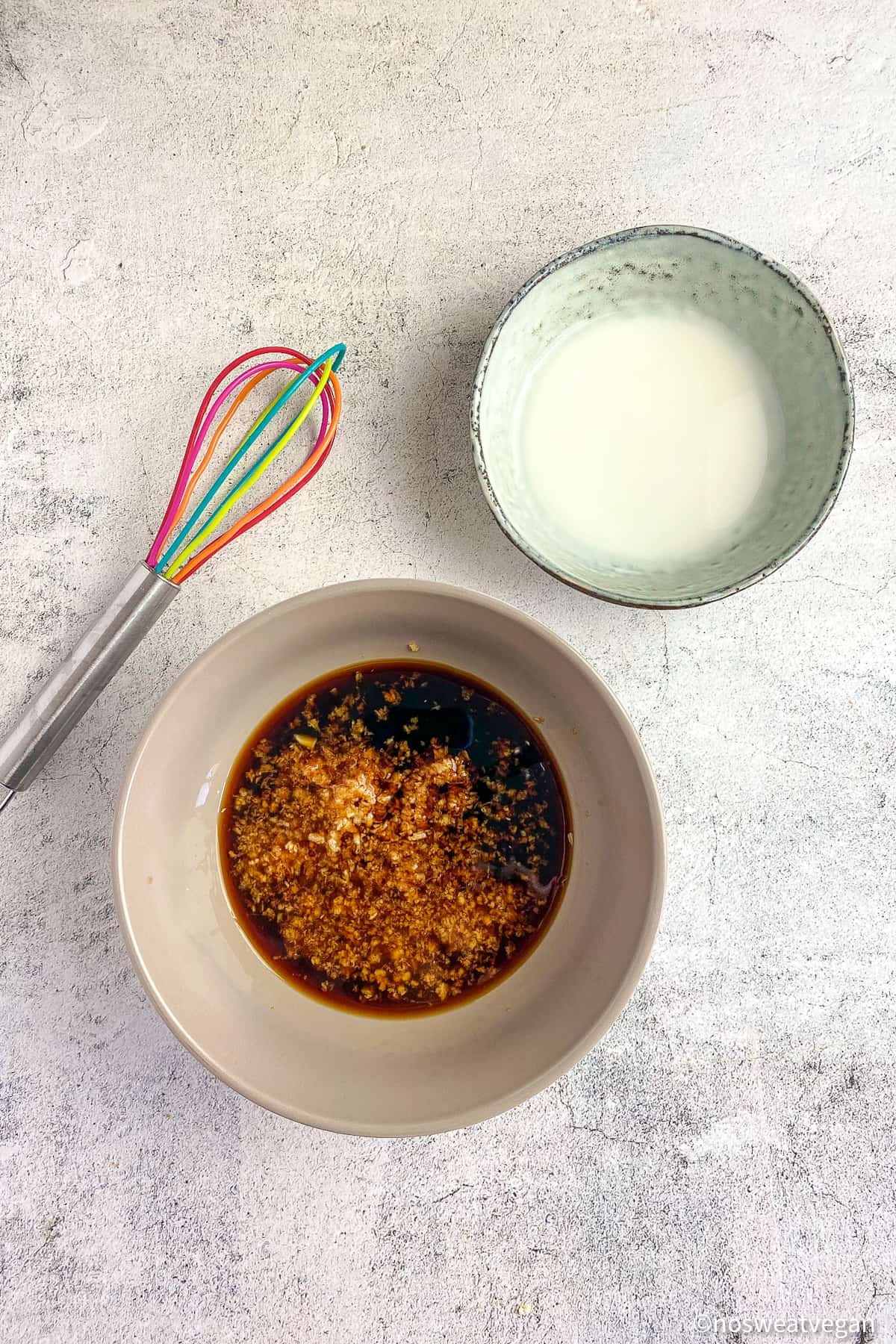 Teriyaki sauce in a bowl next to a bowl of cornstarch slurry and a whisk.