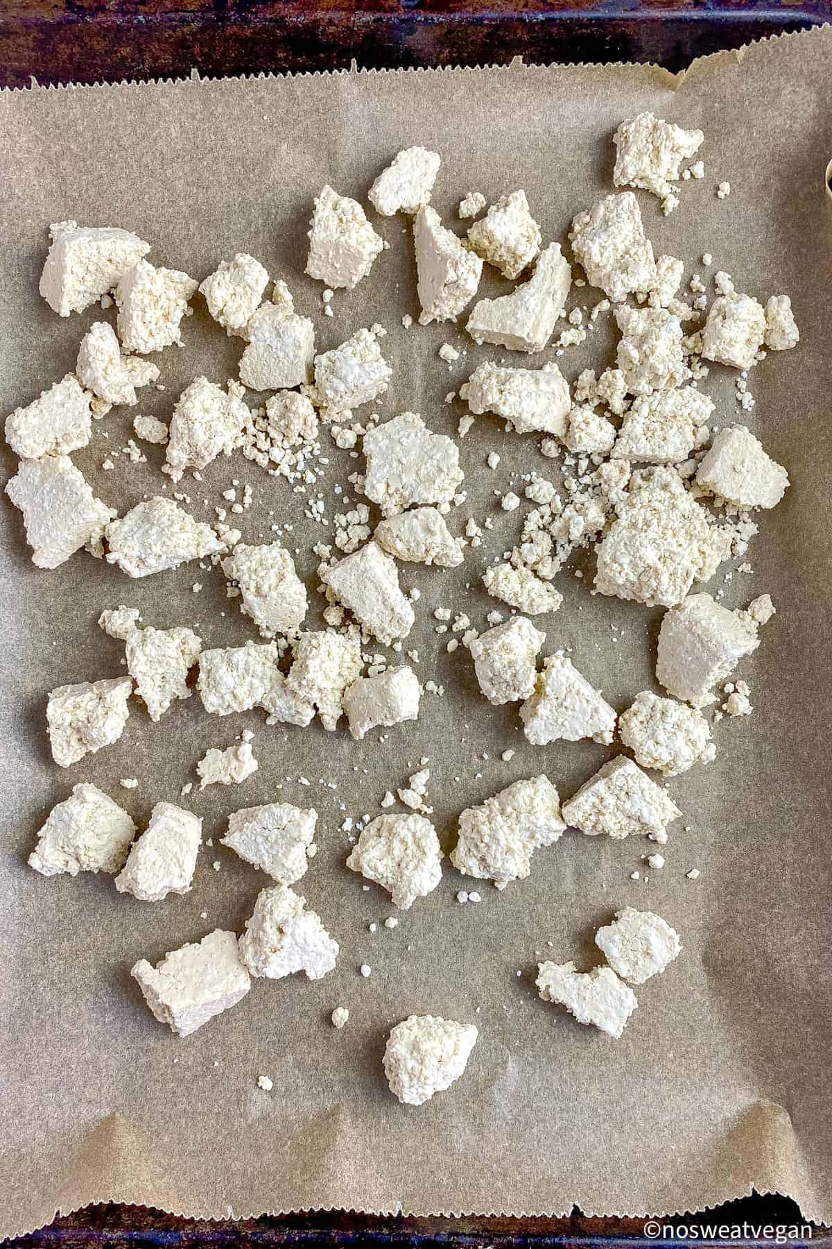 Baking sheet with uncooked tofu chunks.