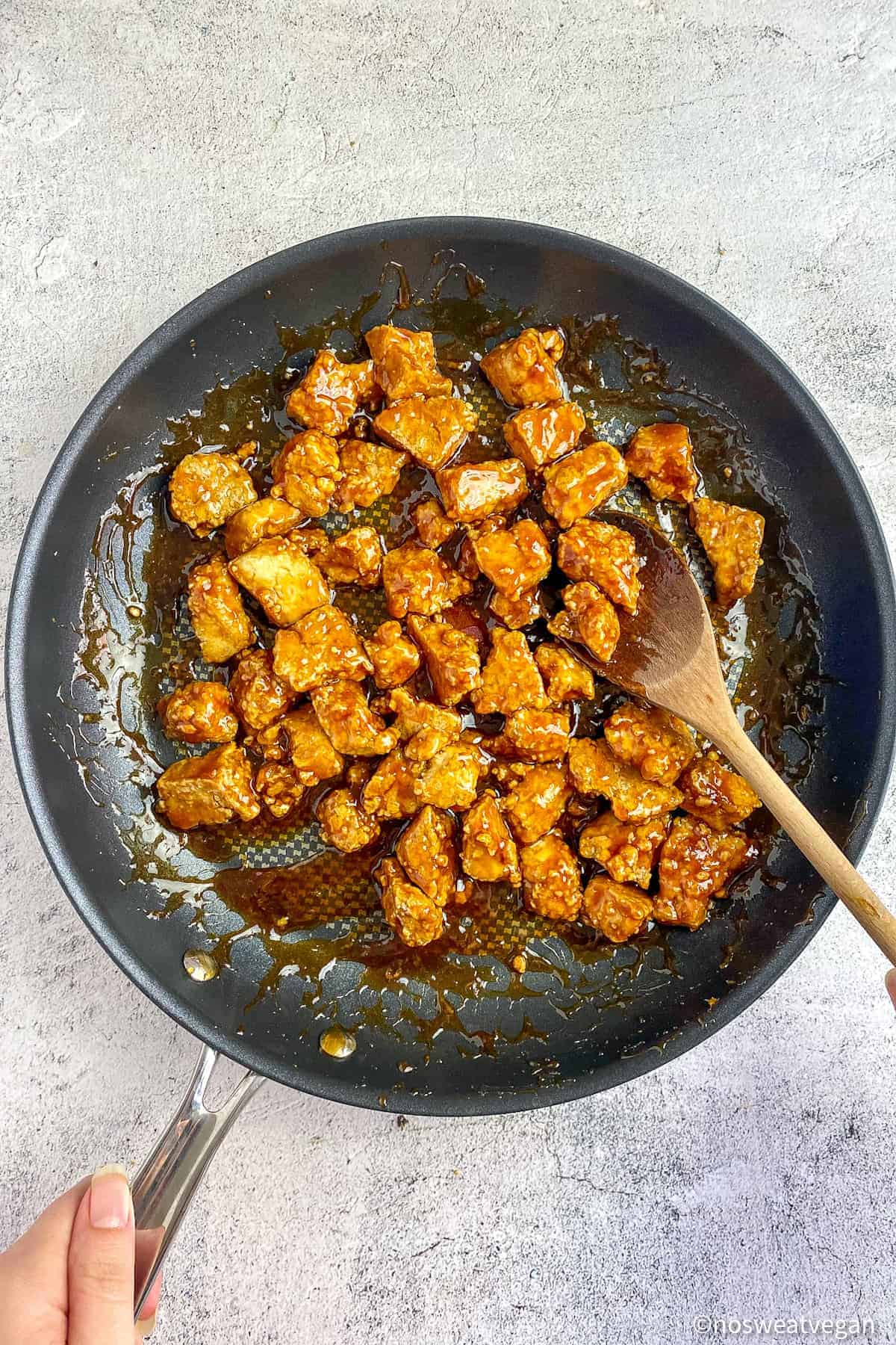 Tofu chunks mixed into teriyaki sauce in a skillet.