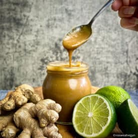 Tahini ginger dressing in a jar with a hand lifting a spoonful out.