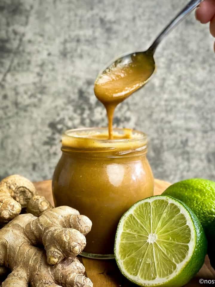 Tahini ginger dressing in a jar with a hand lifting a spoonful out.