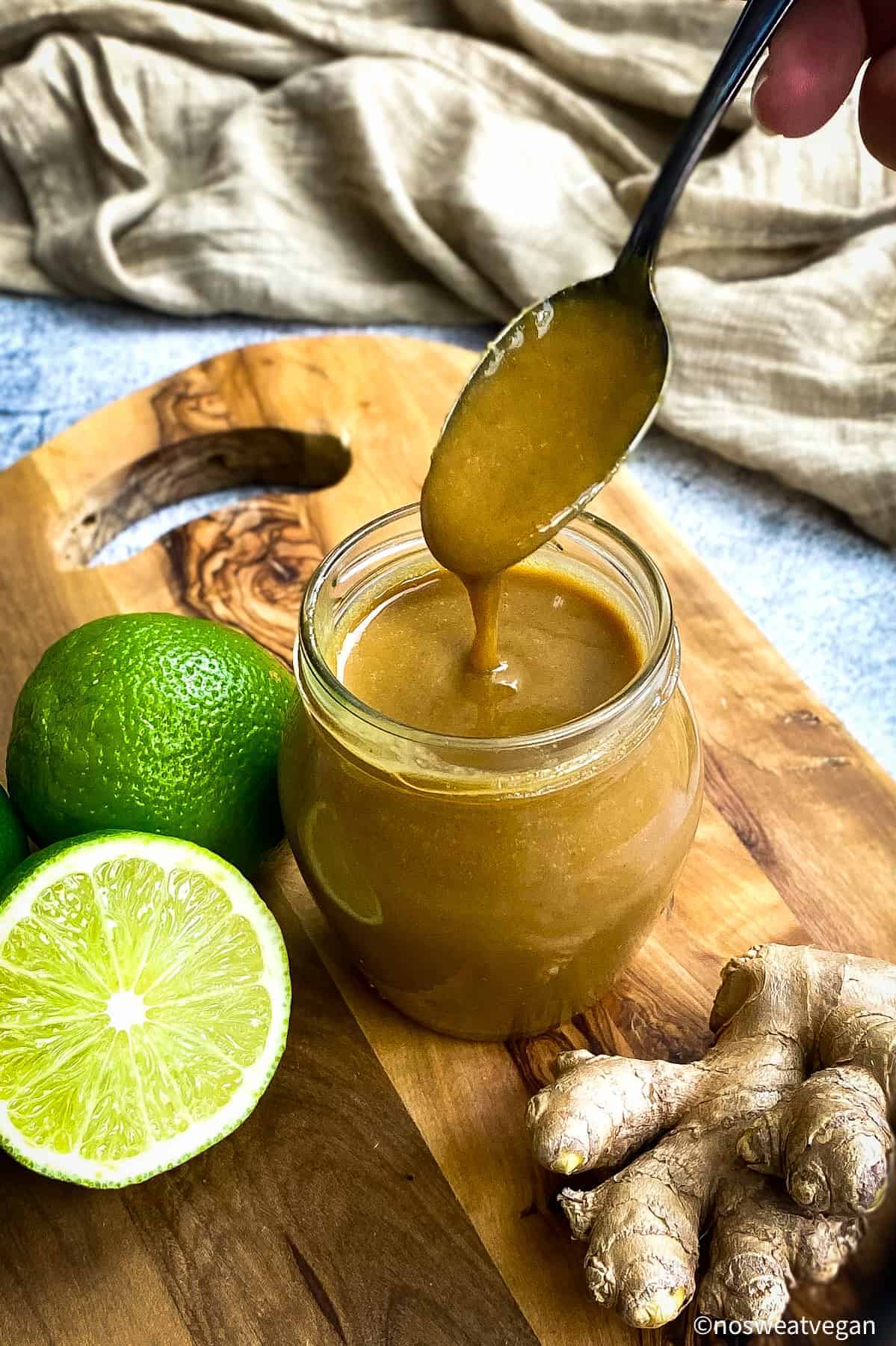 Tahini dressing in a jar with a hand lifting a spoonful out.