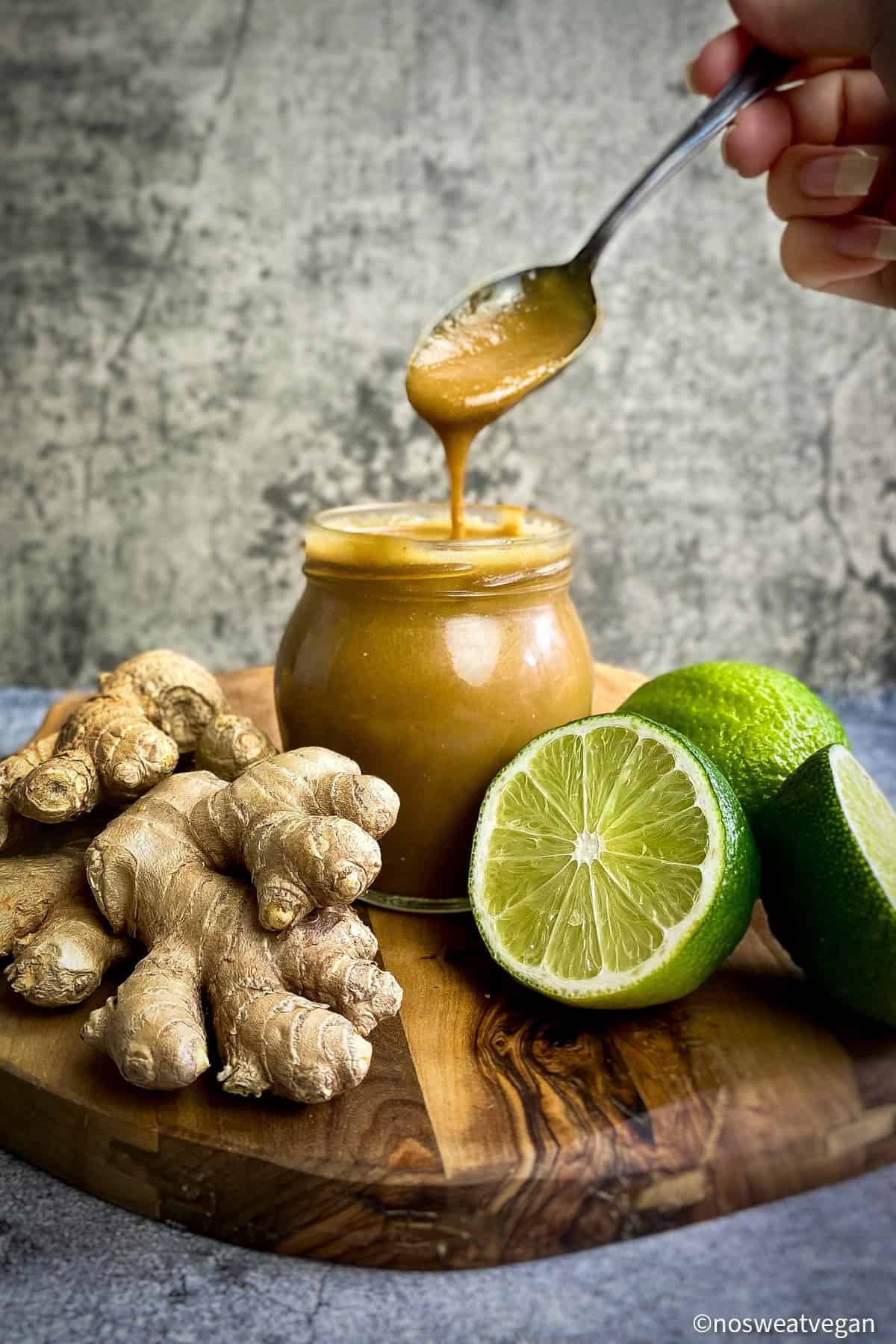 Tahini ginger dressing in a jar with a hand lifting a spoonful out.