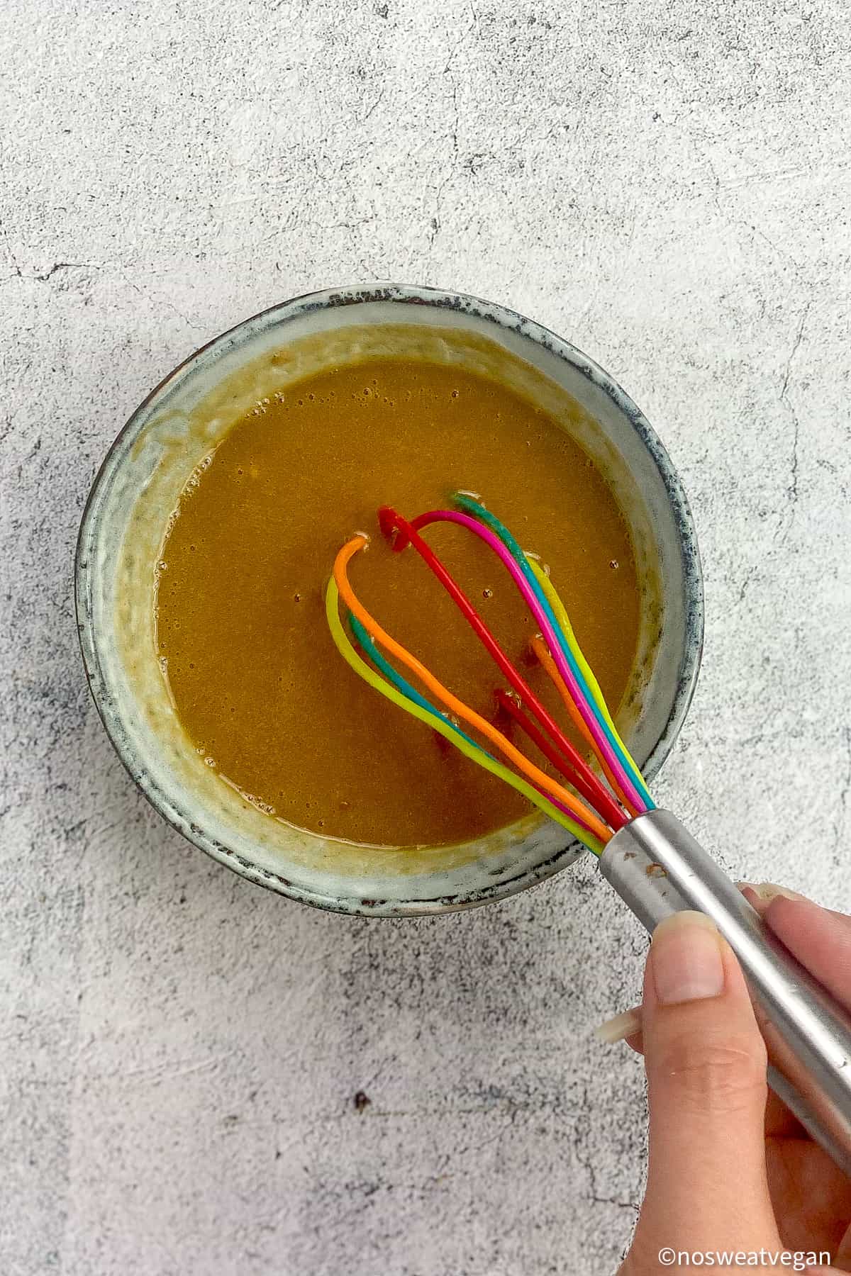 Hand whisking ginger tahini dressing.