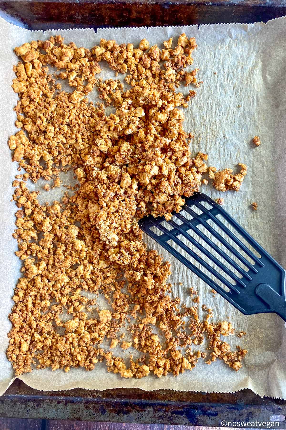 Tofu taco crumbles on a tray with a spatula.