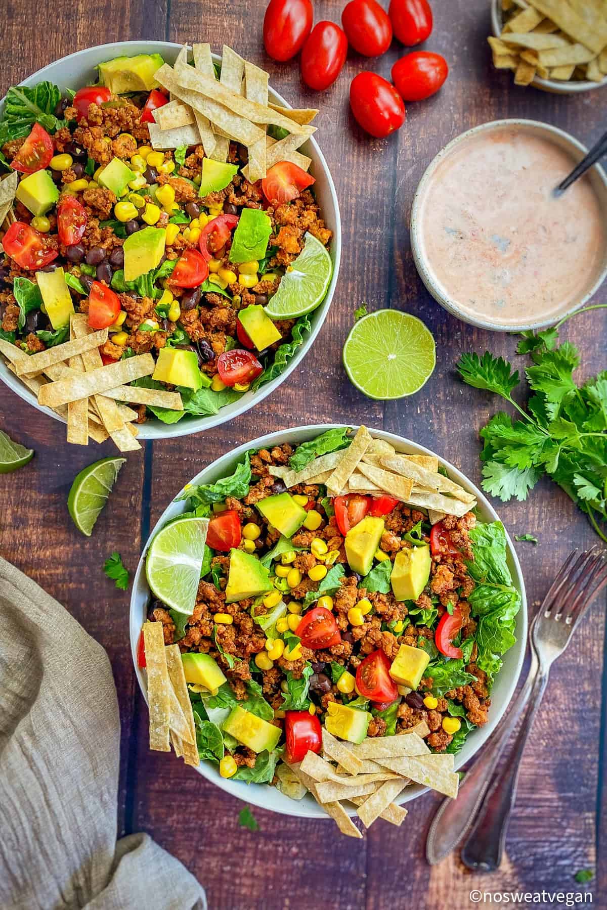 Two bowls of vegan taco salad next to a bowl of dressing.