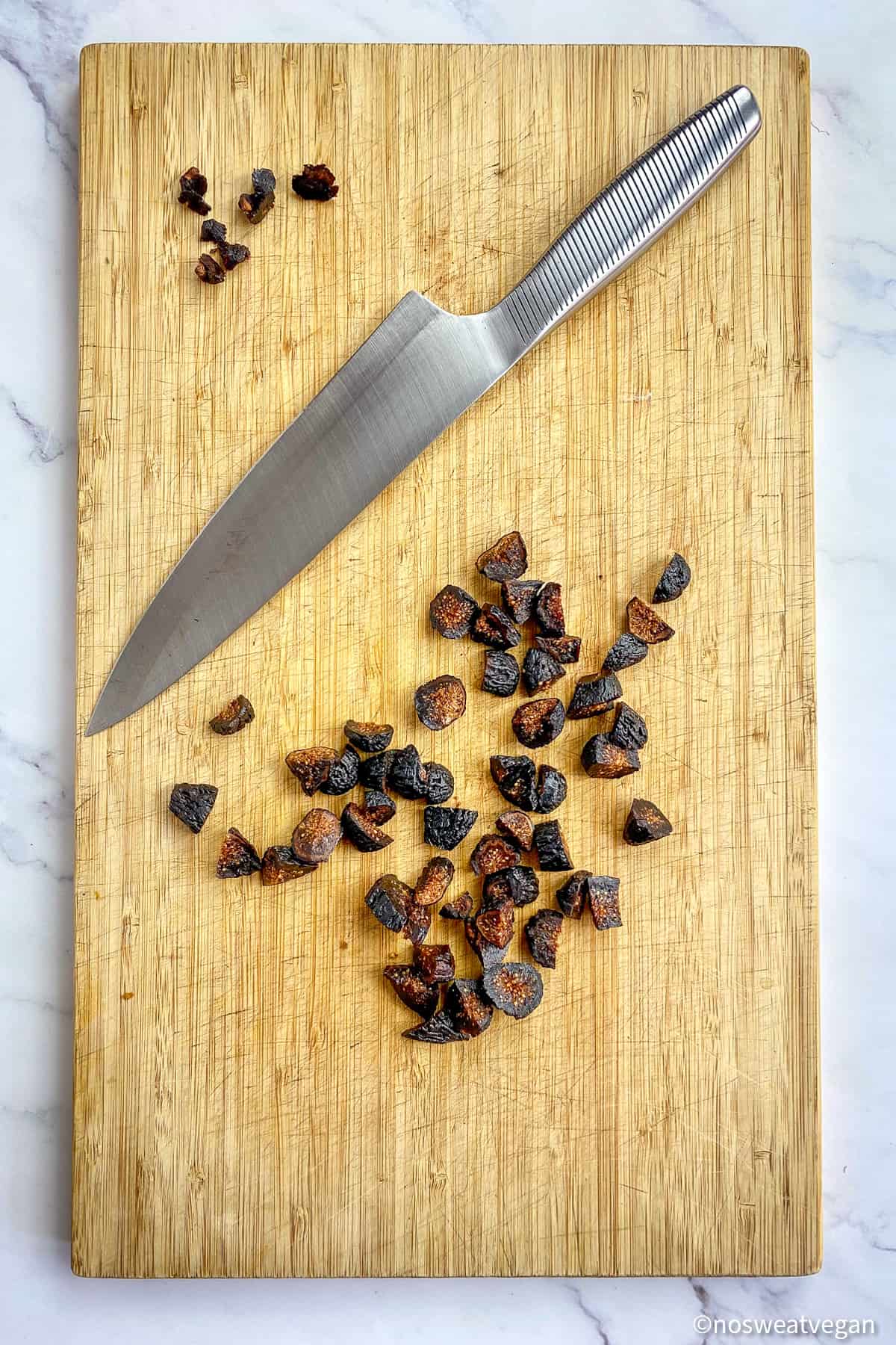 Chopped figs on a cutting board with a knife.