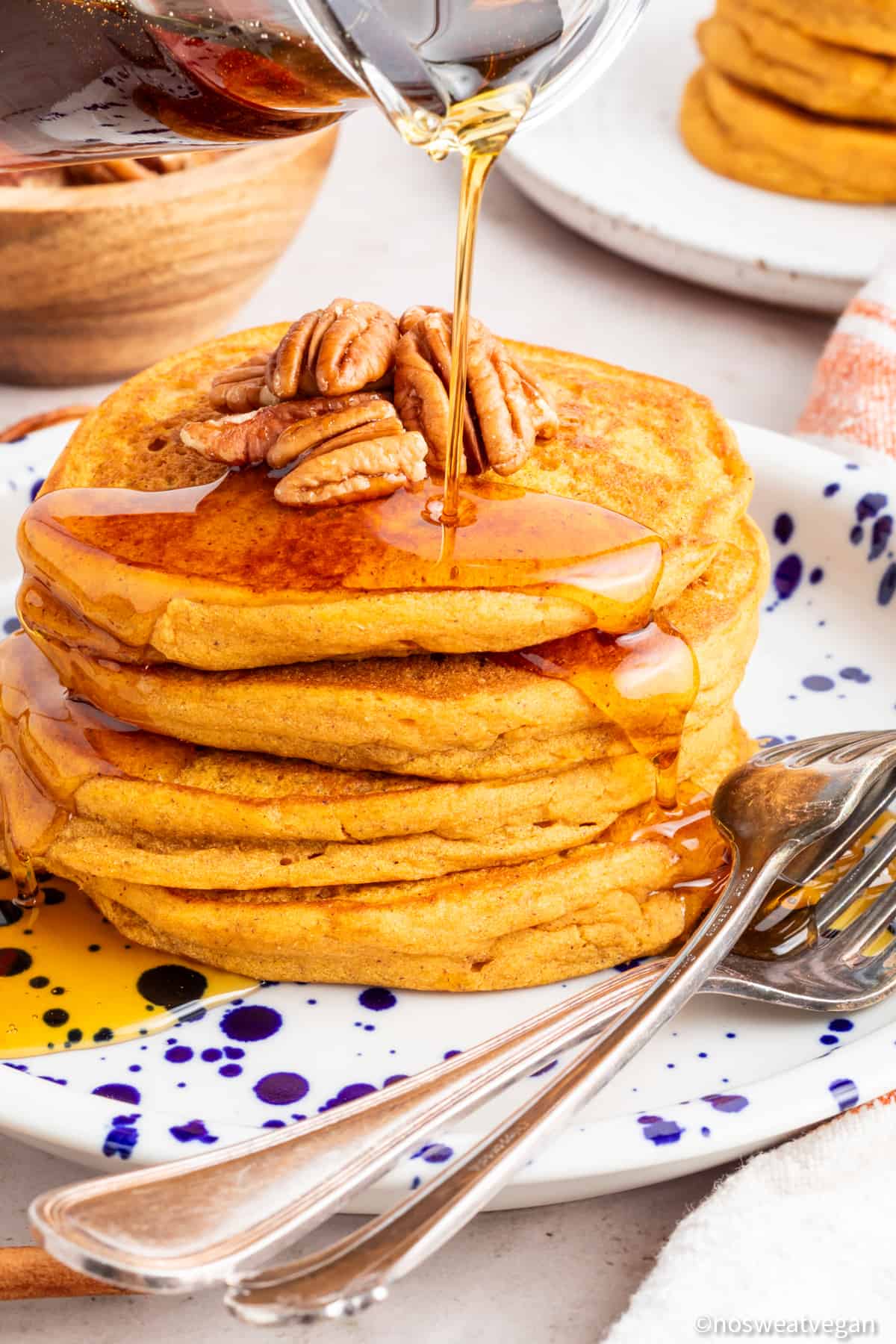 Vegan sweet potato pancakes on a plate with syrup pouring over.