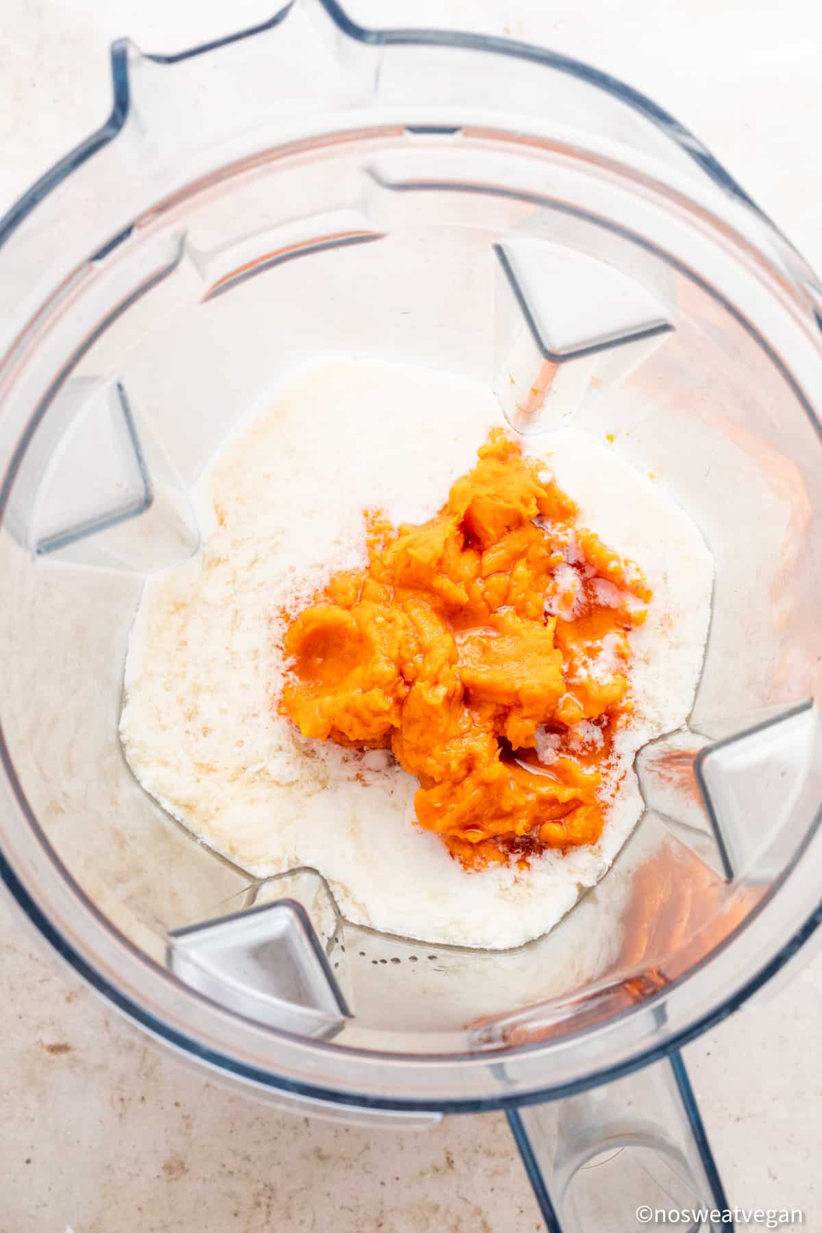 Mashed sweet potatoes and wet ingredients in a blender.