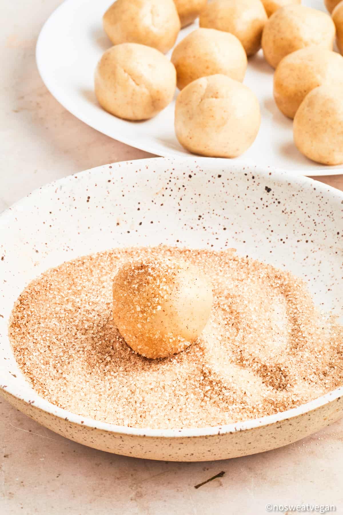 Rolling vegan snickerdoodle dough in cinnamon and sugar.