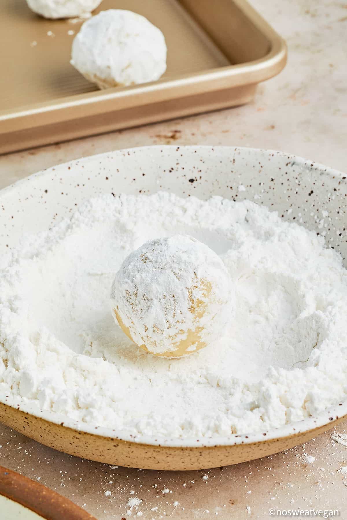 Vegan lemon cookies rolled in powdered sugar.