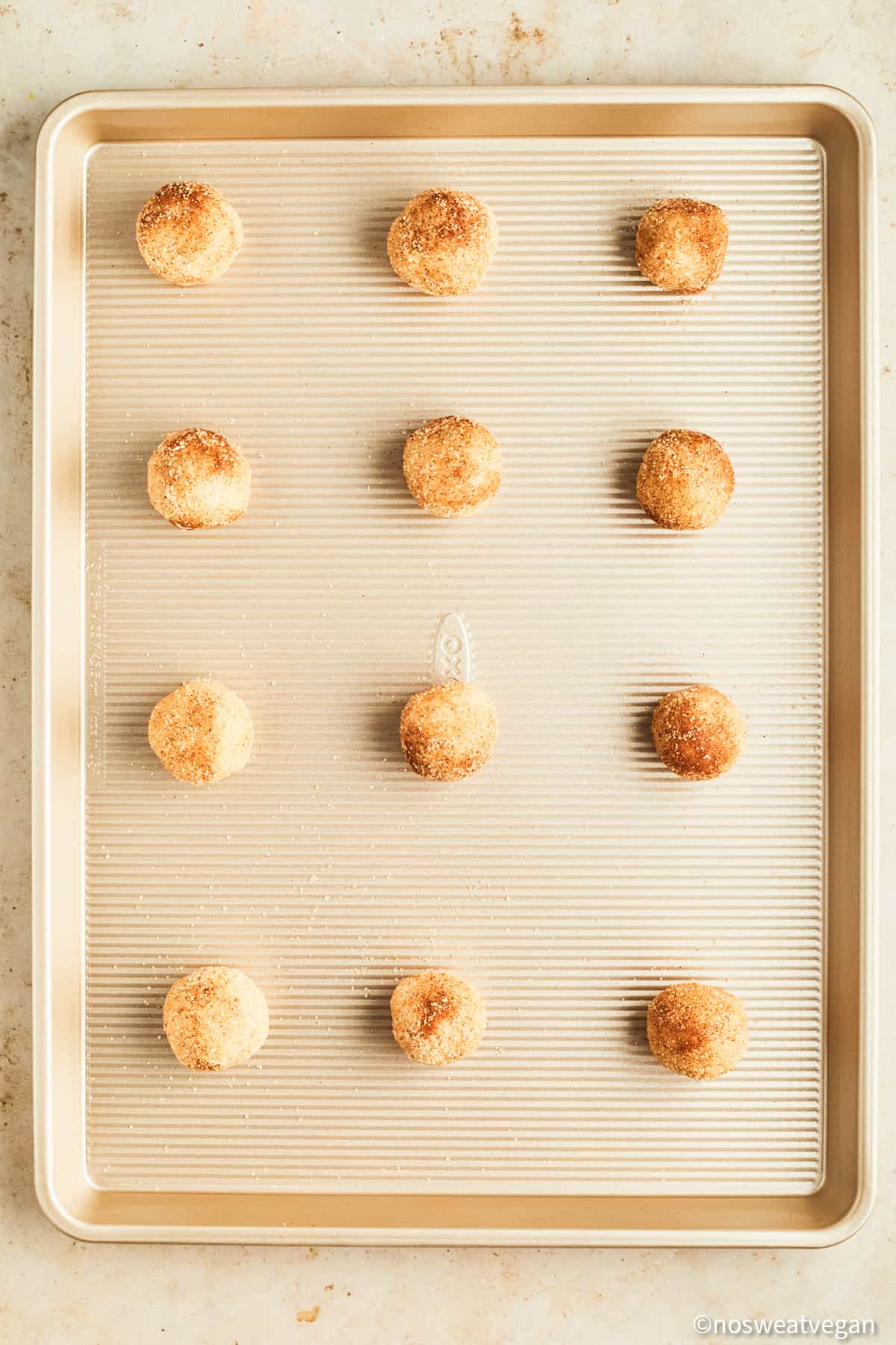 Vegan snickerdoodles uncooked on a baking sheet.