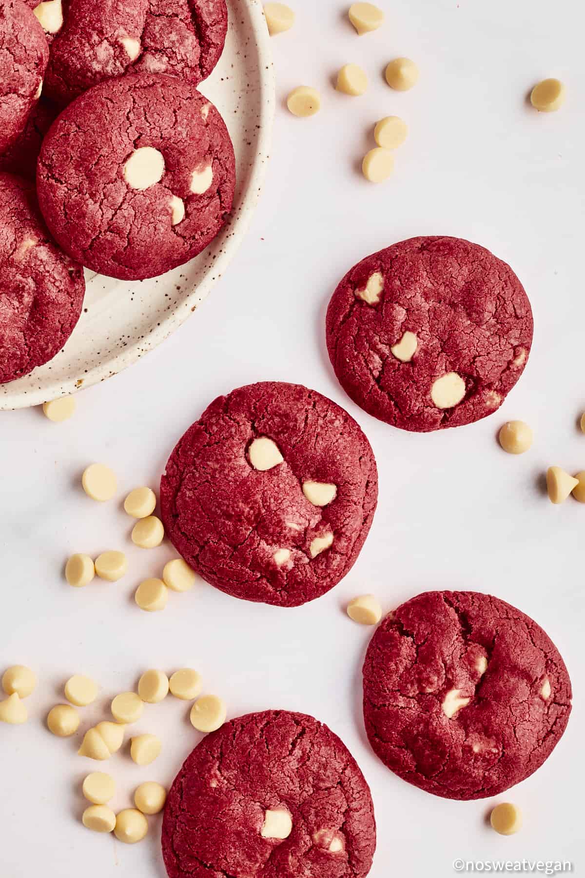 Vegan red velvet cookies on a white background next to a plate of cookies.